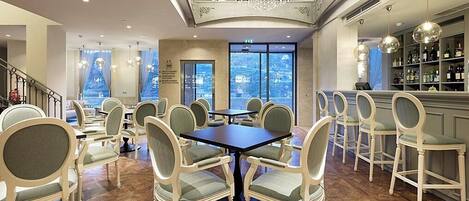 A spacious dining area with high ceilings, a chandelier, and a view of the city.