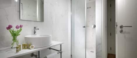 A modern bathroom with a white sink, mirror, and shower.