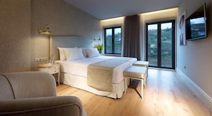 A modern bedroom with a large bed, bedside tables, a bench, and a TV on the wall. - Eurostars Porto Douro (Porto)