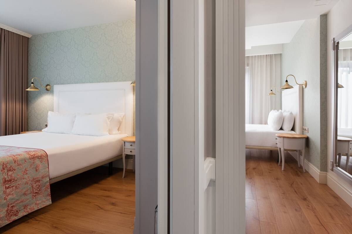 A hotel room with a large bed, bedside tables, and a window with curtains.
