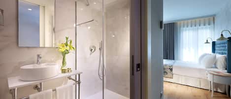 A modern bathroom with a glass-enclosed shower, a white sink, and a mirror.