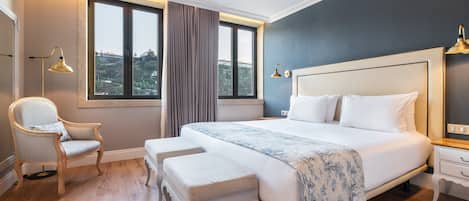 A bedroom with a large bed, a chair, a bench, and a nightstand.