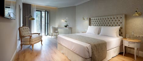 A bedroom with a large bed, a desk, a chair, and a nightstand.
