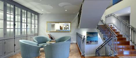 A spacious living area with a herringbone wood floor, a staircase with a metal railing, and a large mirror on the wall.