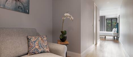 A modern living room with a grey sofa, a patterned pillow, and a potted orchid.