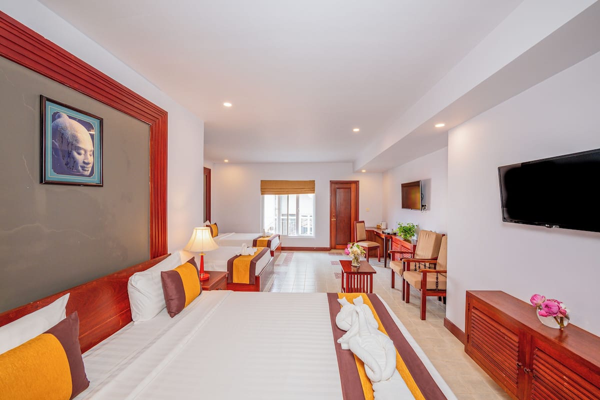 A hotel room with two beds, a TV, a desk, and a view of the outdoors.