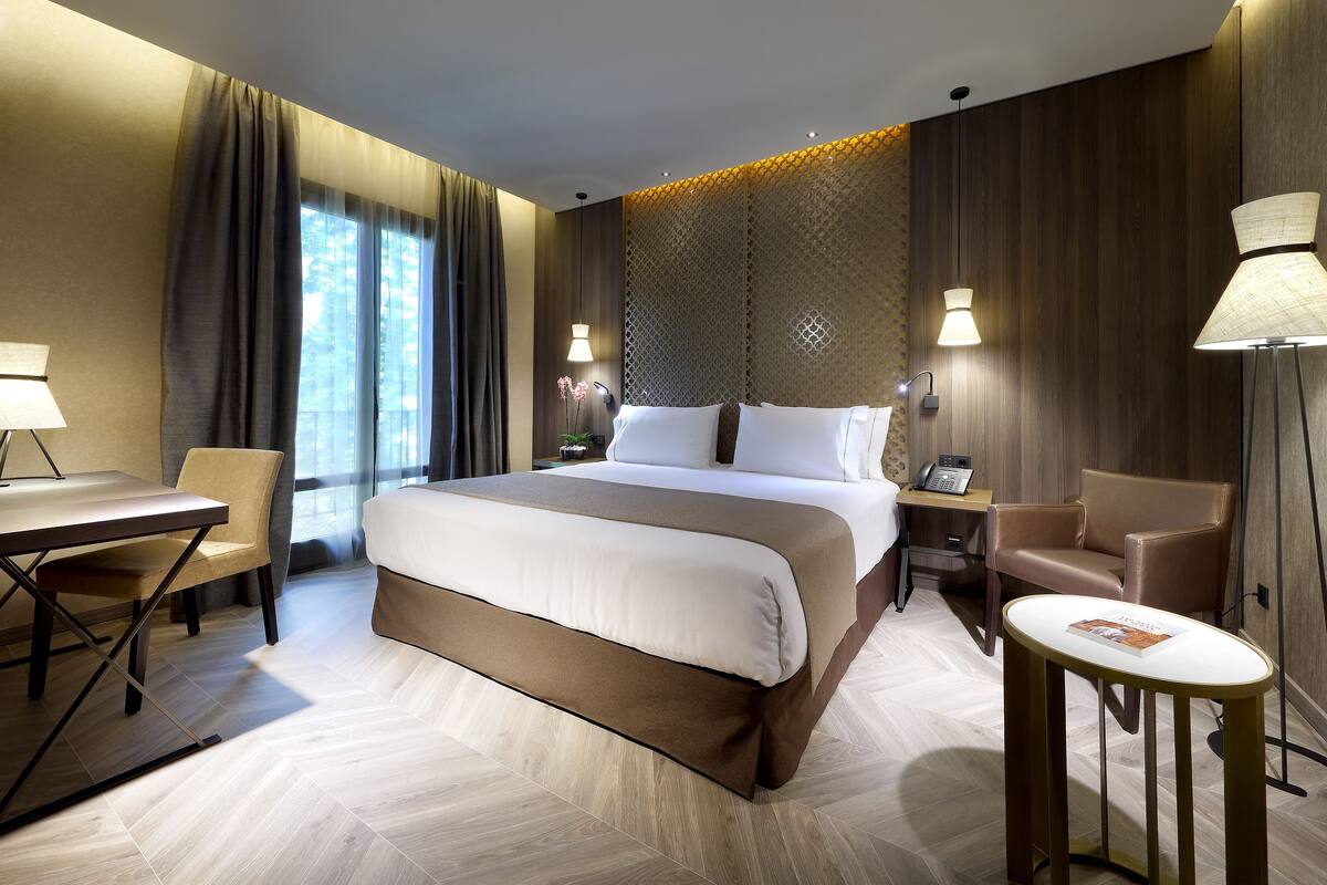 Ein modernes Hotelzimmer mit einem großen Bett, einem Schreibtisch, einem Stuhl und einem kleinen Tisch.