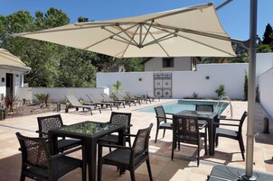 A poolside area with lounge chairs, a table, and an umbrella.