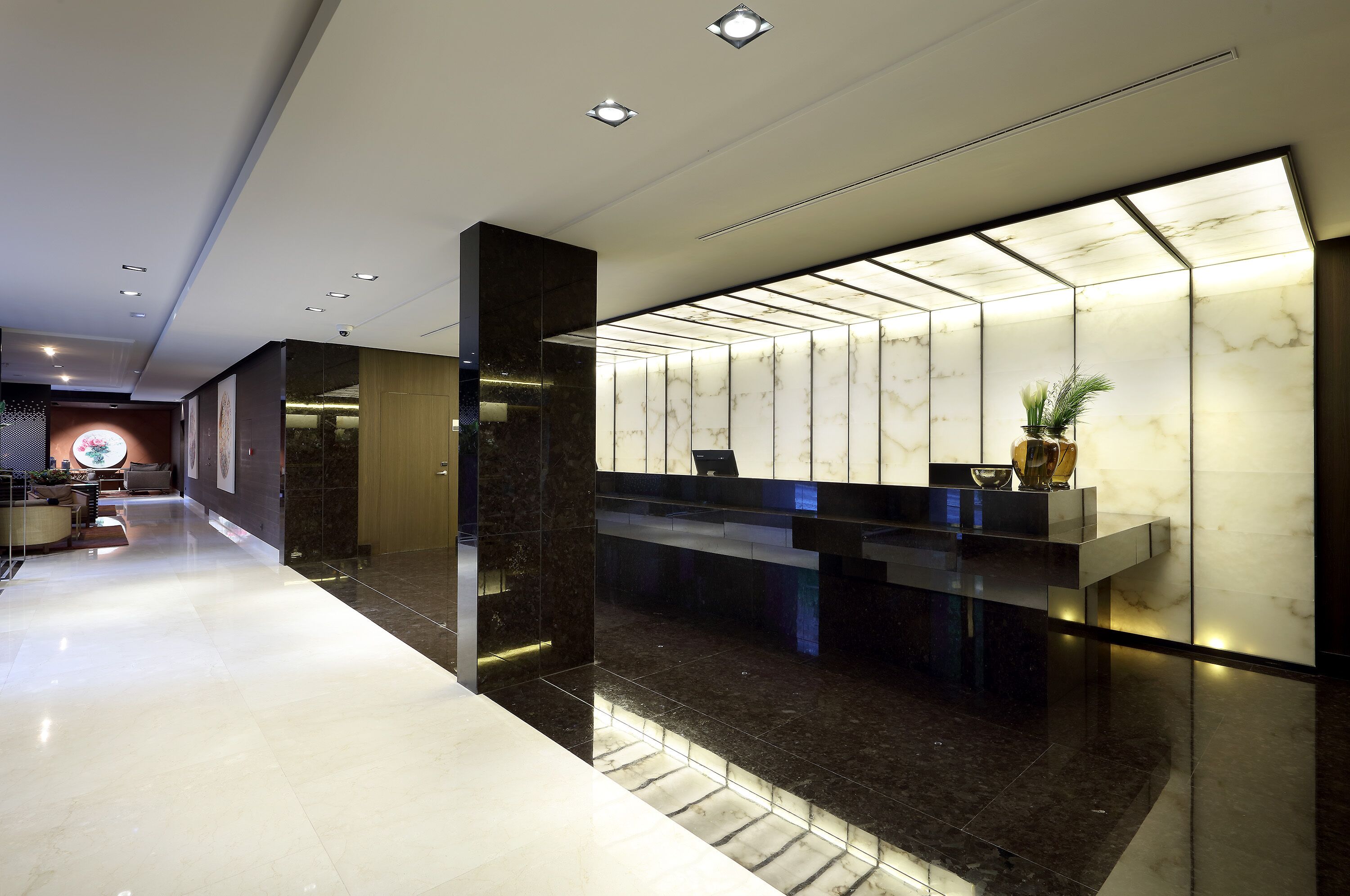 A modern reception area with a marble reception desk, a glass partition, and a potted plant.
