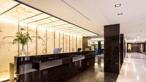 A modern hotel reception area with a marble reception desk, a glass partition, and a clean, polished floor.