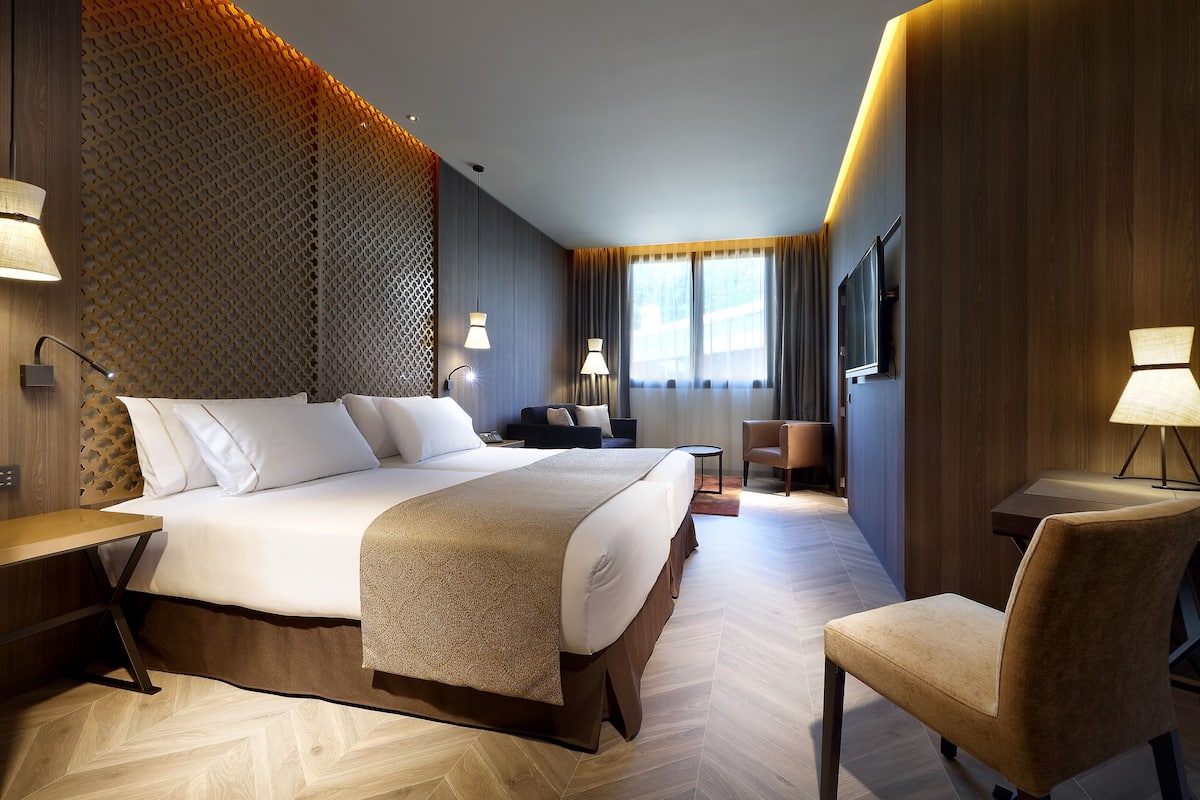 Ein Hotelzimmer mit einem großen Bett, einem Schreibtisch, einem Stuhl und einem Fernseher.