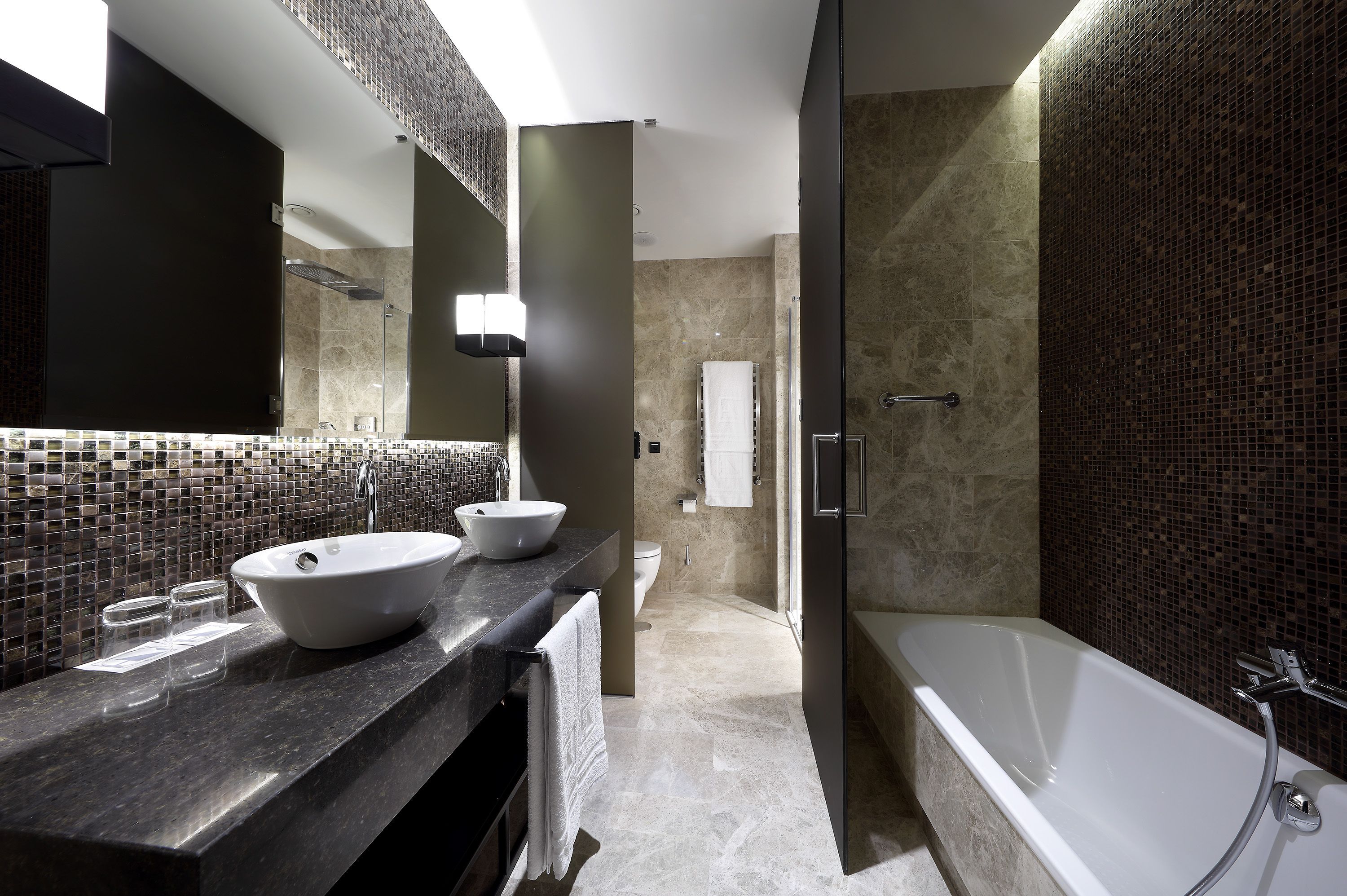 Ein modernes Badezimmer mit einer großzügigen Badewanne, einem Doppelwaschbecken mit Hängebecken und einer Duschkabine.