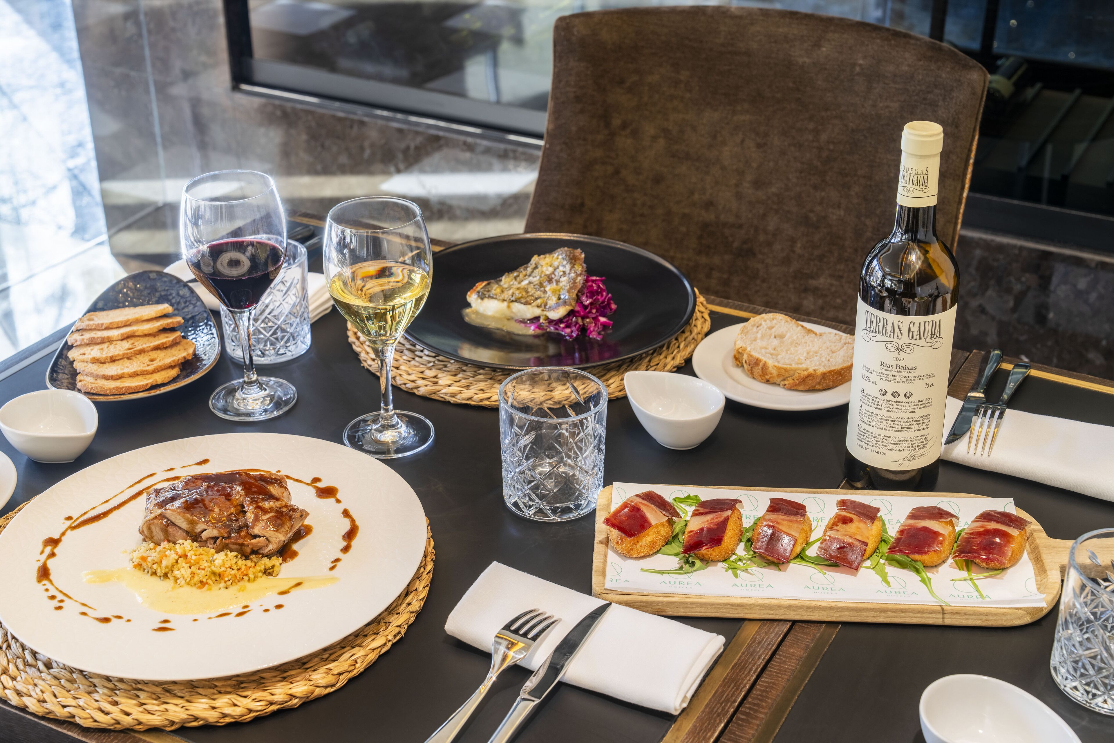 A dining table set with various dishes, glasses, and a bottle of wine.