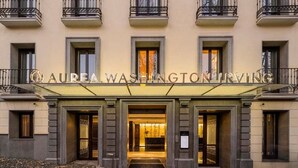 The exterior of the Aurea Washington Irving hotel with a prominent entrance and a balcony.