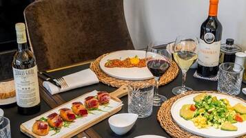 A dining table set with plates of food, glasses of wine, and bottles of wine.
