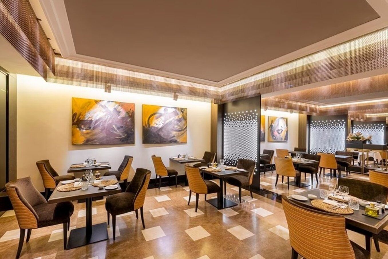 Un comedor amplio con varias mesas y sillas, que presenta arte abstracto en las paredes y un suelo estampado.