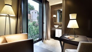 A modern hotel room with a balcony, a dining area with a table and chairs, and a bathroom with a large mirror and a sink.