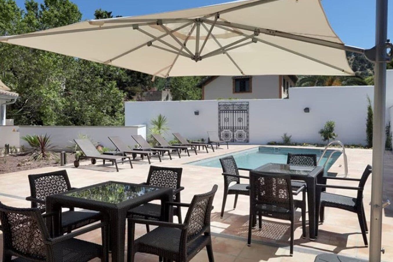 Un área de piscina al aire libre con sillones de descanso y una mesa.