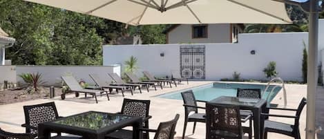 Un área de piscina al aire libre con sillones de descanso y una mesa.