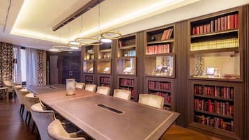 Una sala de conferencias con una larga mesa, sillas y estanterías llenas de libros.