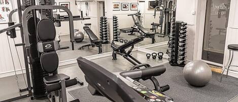 A gym with various exercise equipment, including a treadmill, weight machines, and free weights.