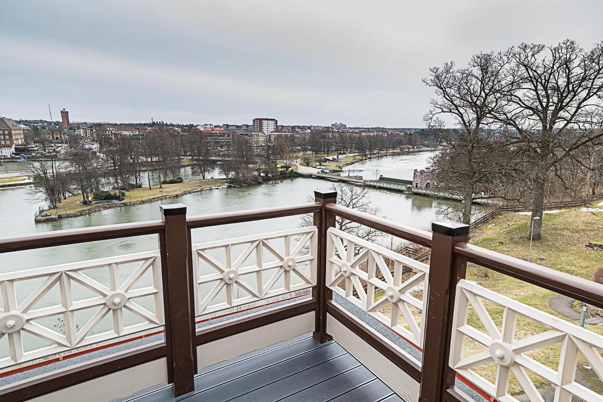 Un balcón con vista a un río, edificios y un árbol.