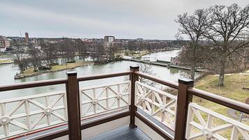 Un balcón con vista a un río, edificios y un árbol.
