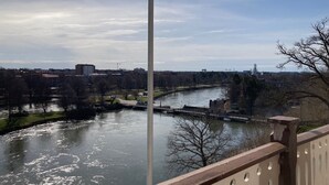 Un río con un puente, árboles y edificios al fondo.