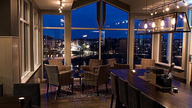 Un comedor moderno con grandes ventanales que ofrecen vista a la ciudad de noche.