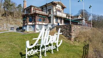 A two-story building with a balcony, a stone wall, and a sign reading 'Albert Kok Hotel'.