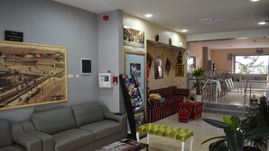 Et hotel lobby med en sofa, en bænk, en magasinholder og et stort maleri.