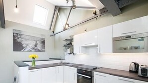 Eine moderne Küche mit weißen Schränken, einem eingebauten Backofen und einer Kaffeemaschine.