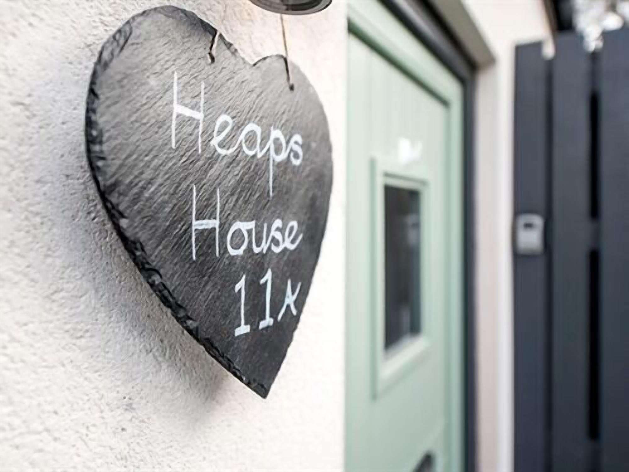A heart-shaped sign with "Heaps House 11x" written on it, attached to a wall.