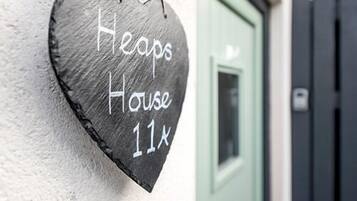 A heart-shaped sign with "Heaps House 11x" written on it, attached to a wall.