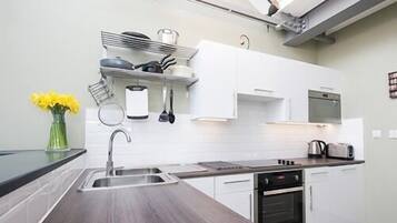 A modern kitchen with a wooden countertop, stainless steel appliances, and white cabinetry.
