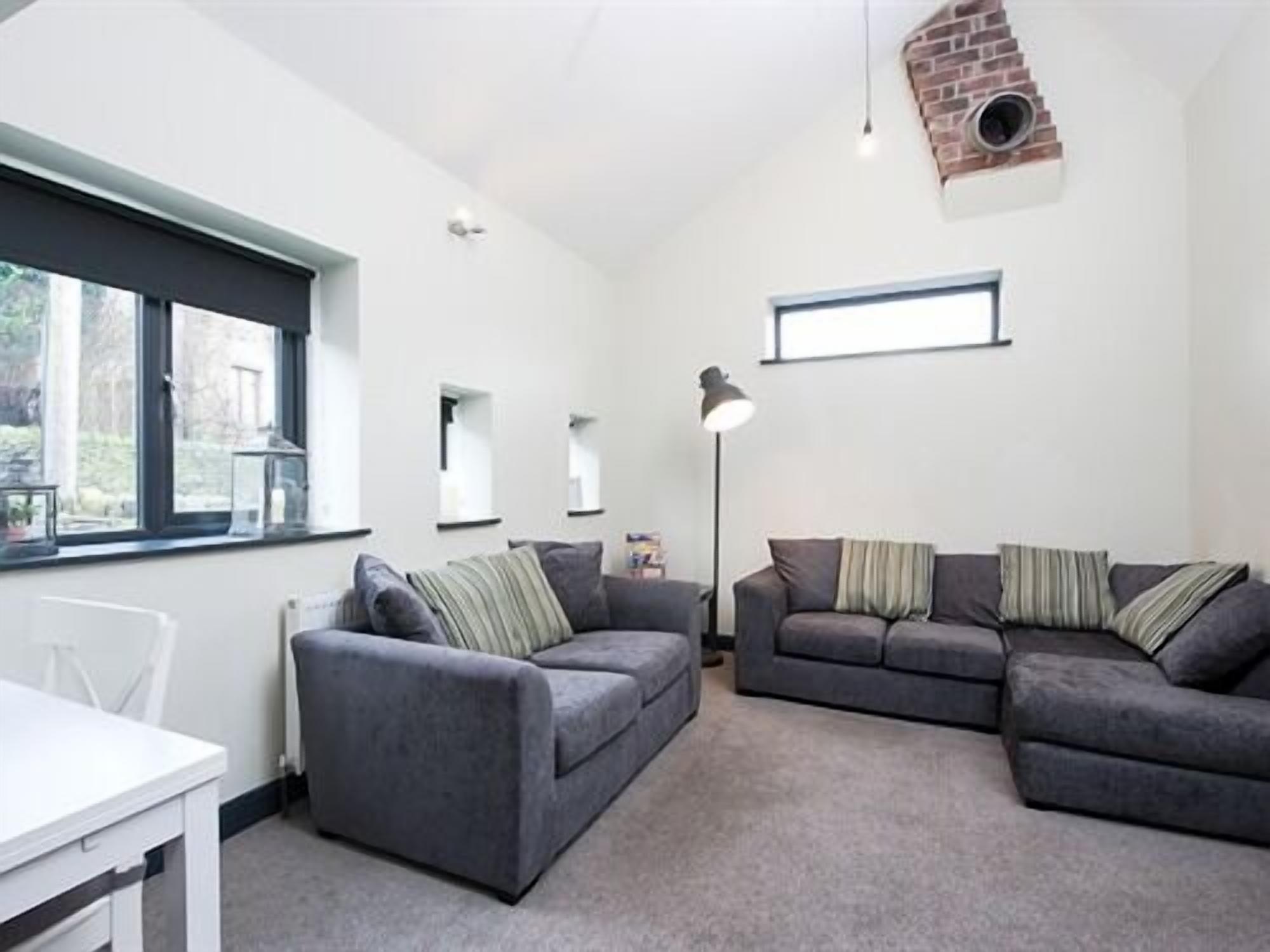 A modern living room with two grey sofas, a white table, and a floor lamp.