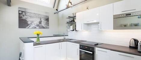 A modern kitchen with white cabinets, a black countertop, and a stainless steel oven.