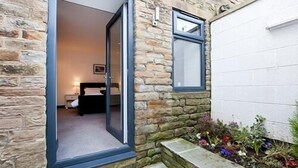 Ein Steinhaus, durch eine Glastür ist ein Schlafzimmer zu sehen.