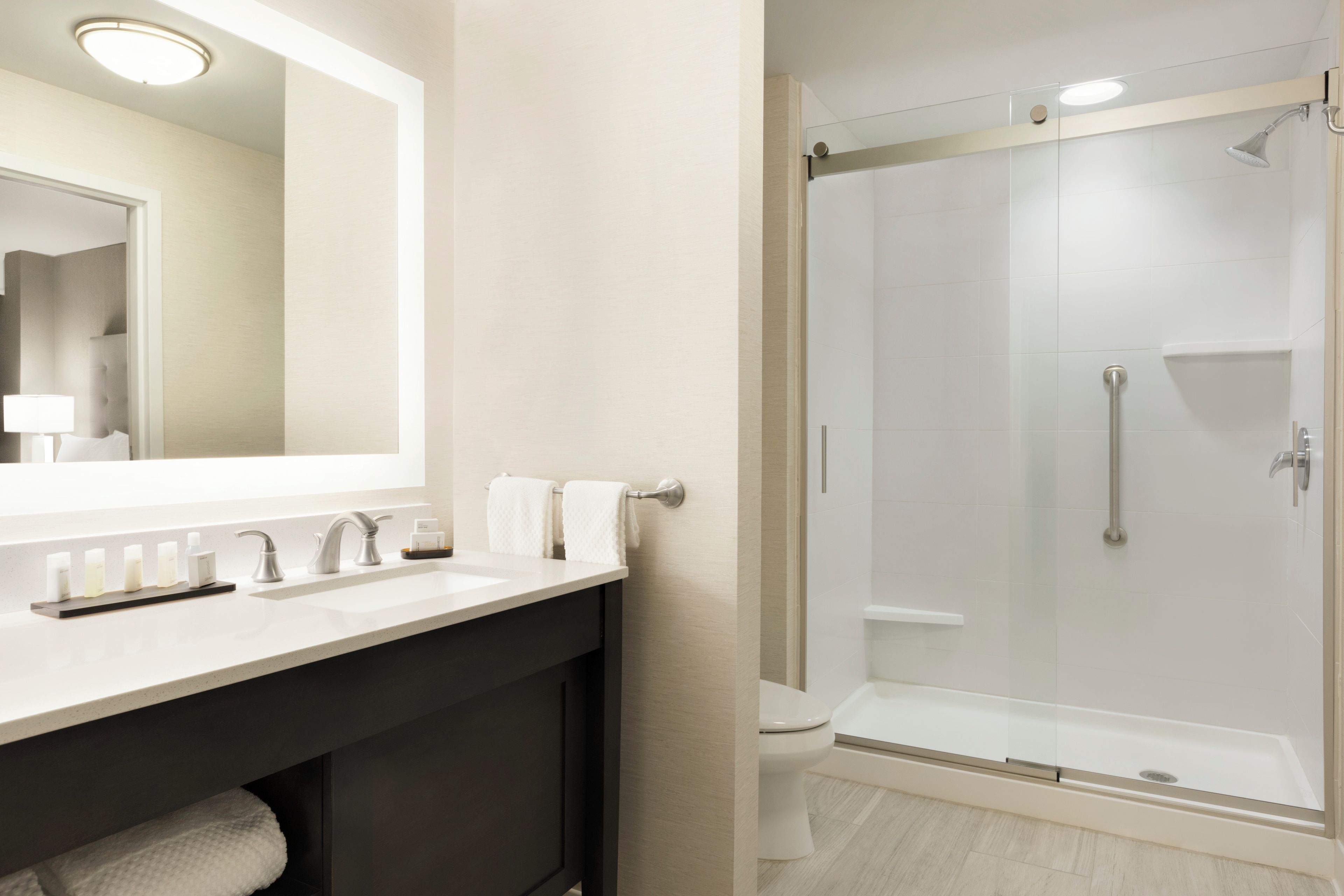 Een moderne badkamer met een grote spiegel, een wastafel en een douche met glazen wanden.