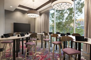 A conference room with multiple tables, chairs, and laptops, equipped with a large screen and modern lighting fixtures. - Embassy Suites by Hilton Greenville Downtown Riverplace (Greenville)