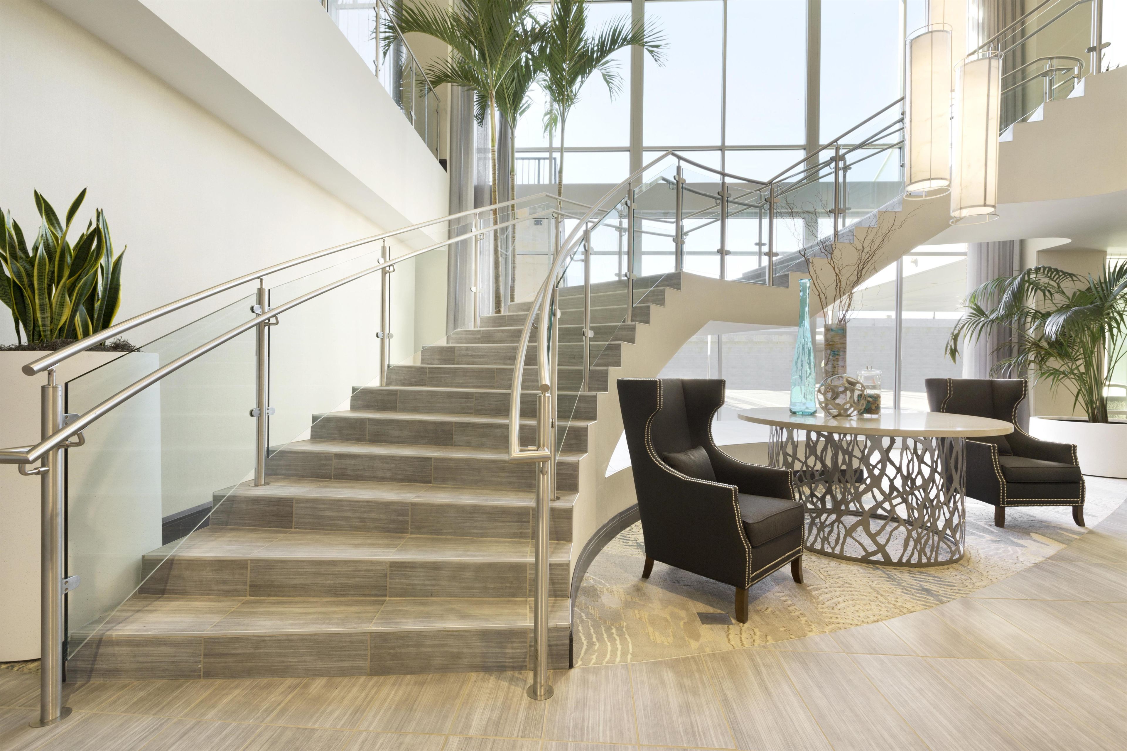A modern interior with a staircase, seating area, and large windows.