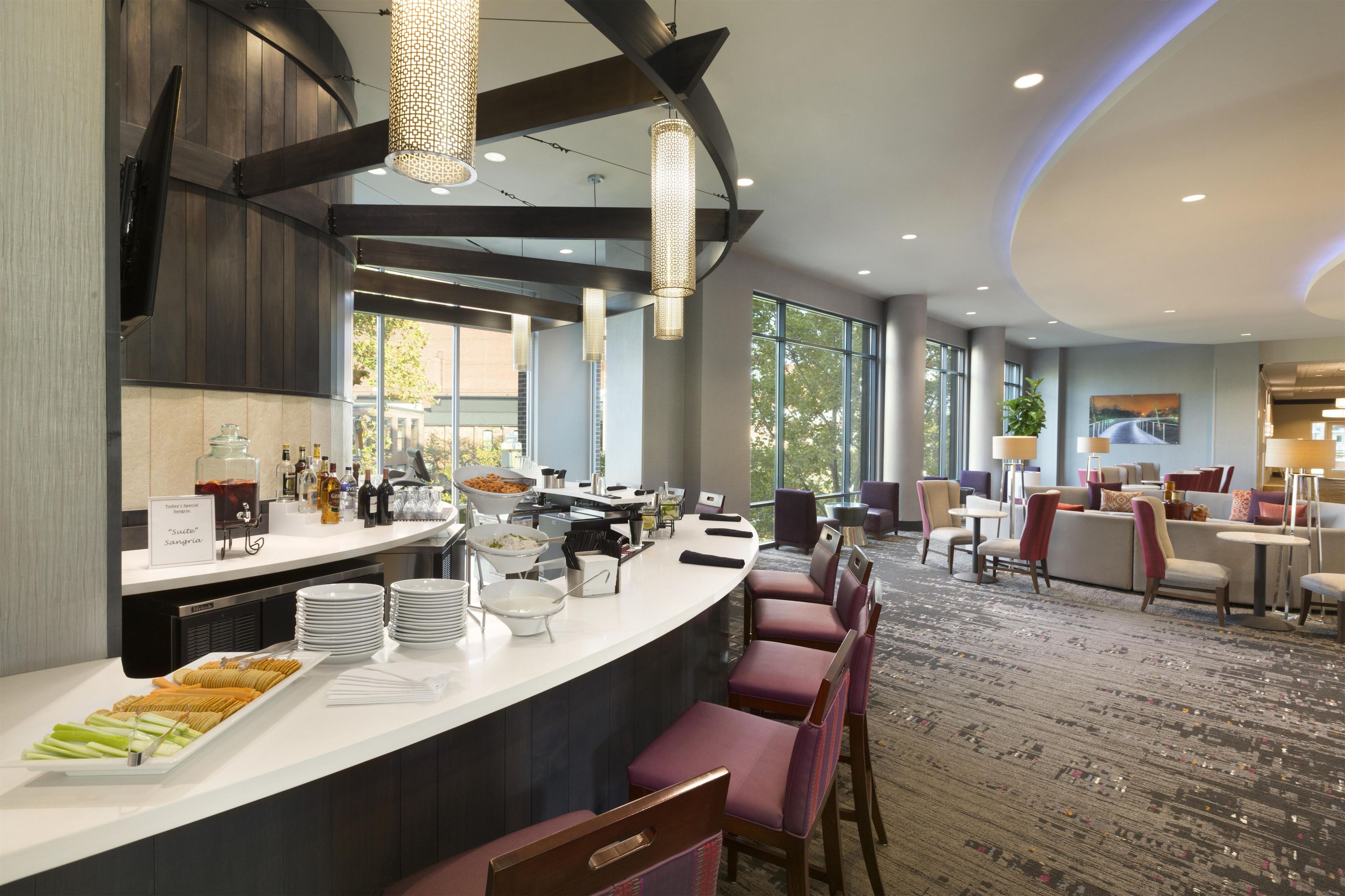 A modern hotel lobby with a bar area, seating, and large windows.
