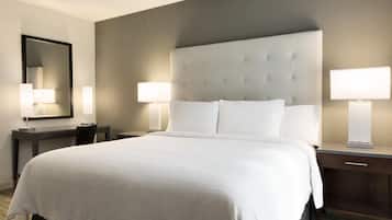 A hotel room with a large bed, two bedside tables, a nightstand, a mirror, and two wall-mounted lamps.