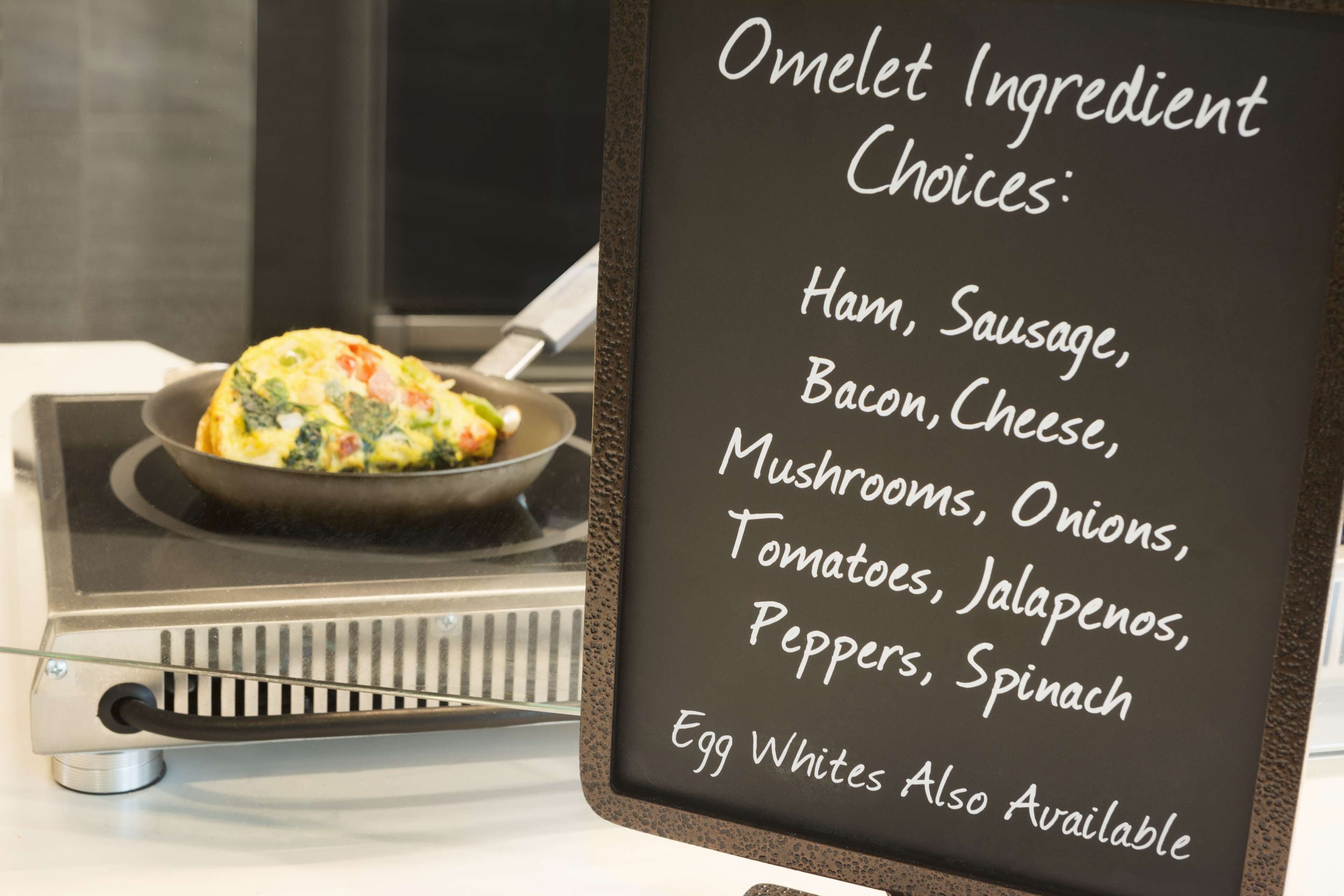A menu board listing omelet ingredient choices such as ham, sausage, bacon, cheese, mushrooms, onions, tomatoes, jalapenos, peppers, spinach, and egg whites.