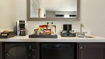 A kitchenette with a coffee maker, microwave, and a tray of snacks.
