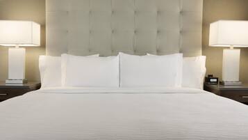 A neatly made bed with a tufted headboard, two bedside lamps, and a digital clock on a bedside table.
