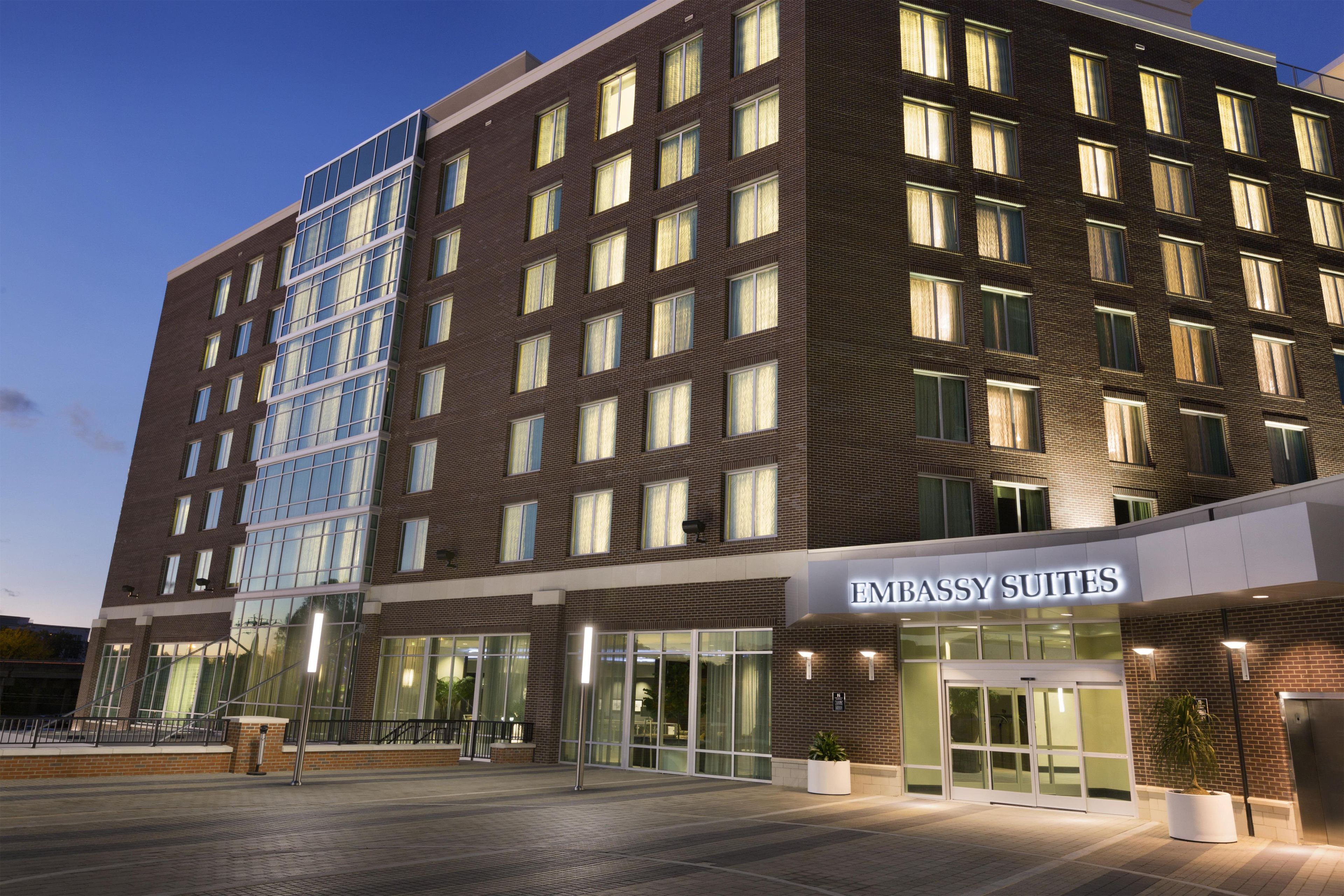 Un hotel su più piani con una vistosa insegna 'EMBASSY SUITES', ampie finestre e facciata in mattoni.
