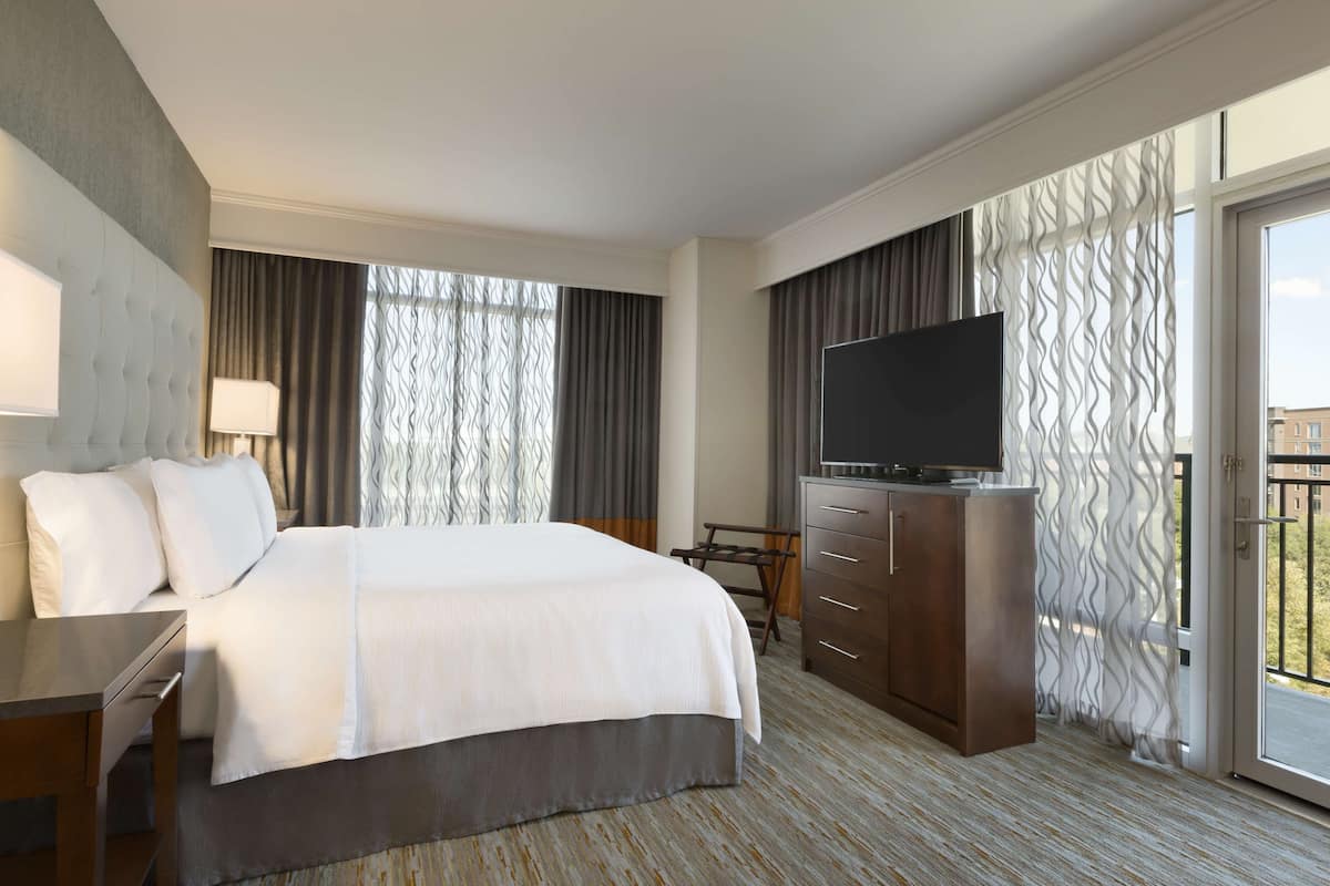 A hotel room with a large bed, a flat-screen TV, a desk, and a dresser.