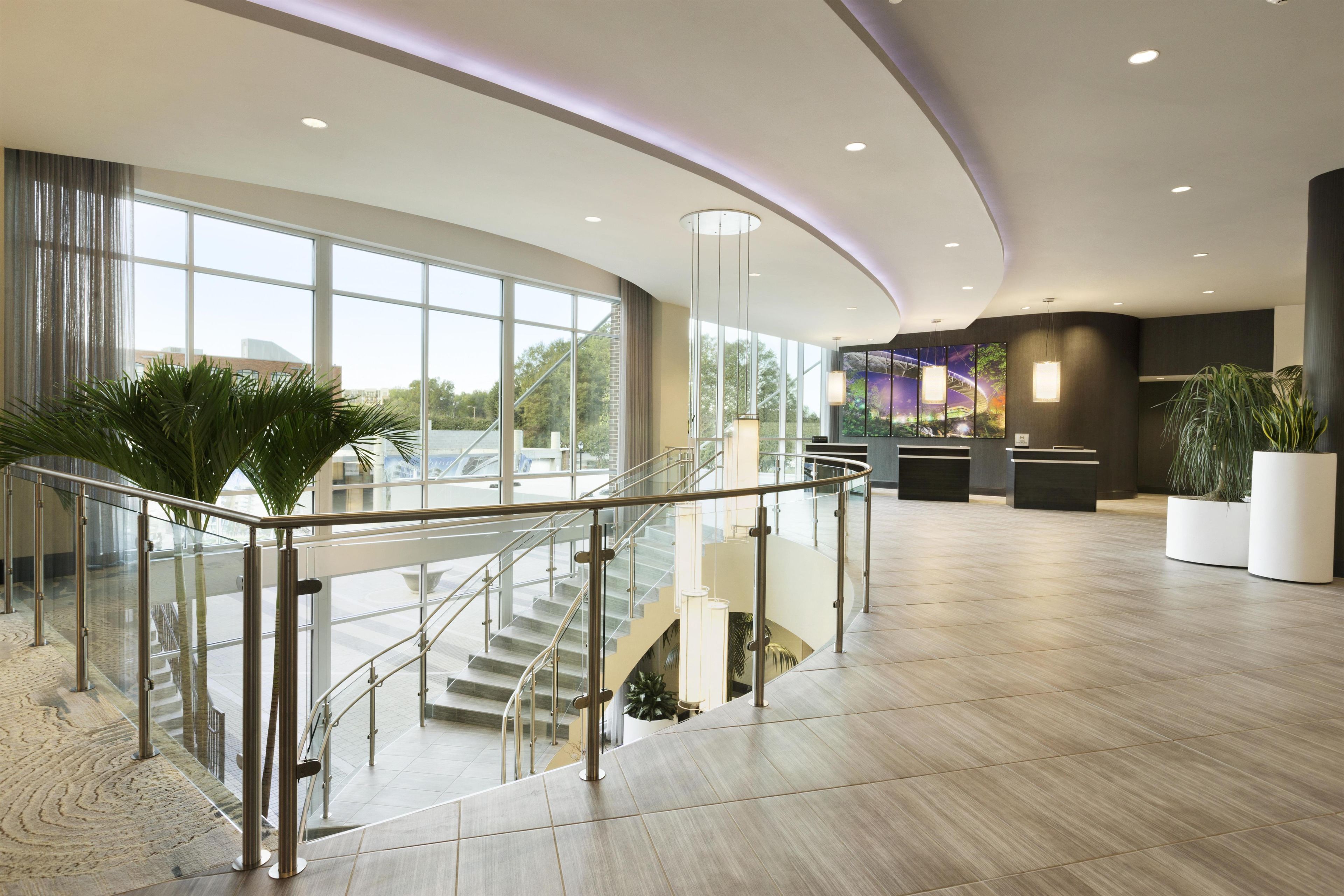 A spacious lobby with a glass railing, a staircase, and a reception desk.