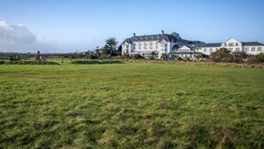 A large, multi-story building with a symmetrical facade, a well-maintained lawn in the foreground, and a clear sky. - Garryvoe Beach Homes (Garryvoe)
